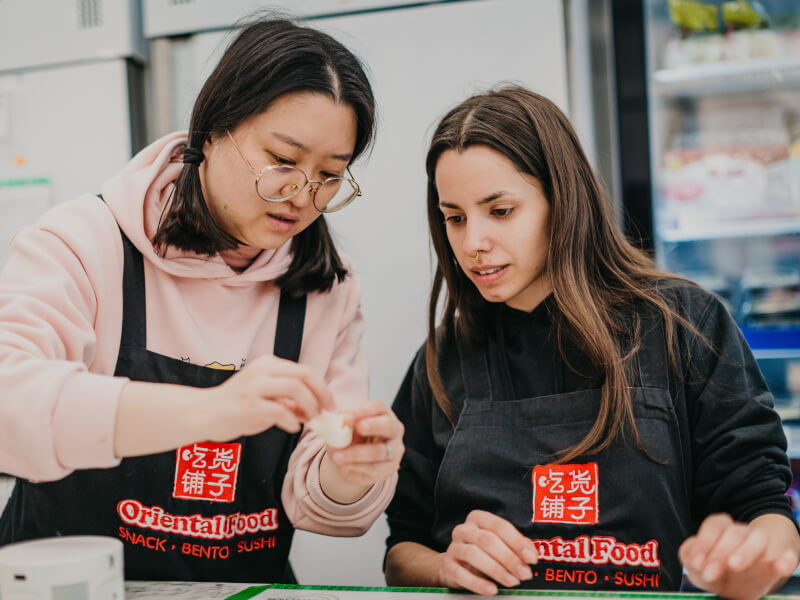 Teacher showing woman how to make dumplings from scratch.